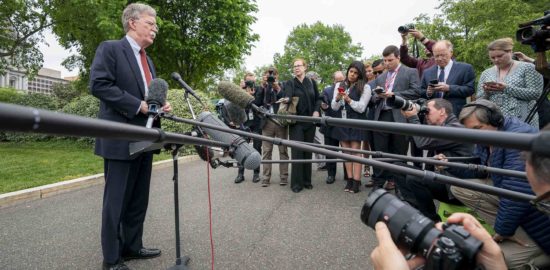John Bolton stands in front of numerous microphones and reporters