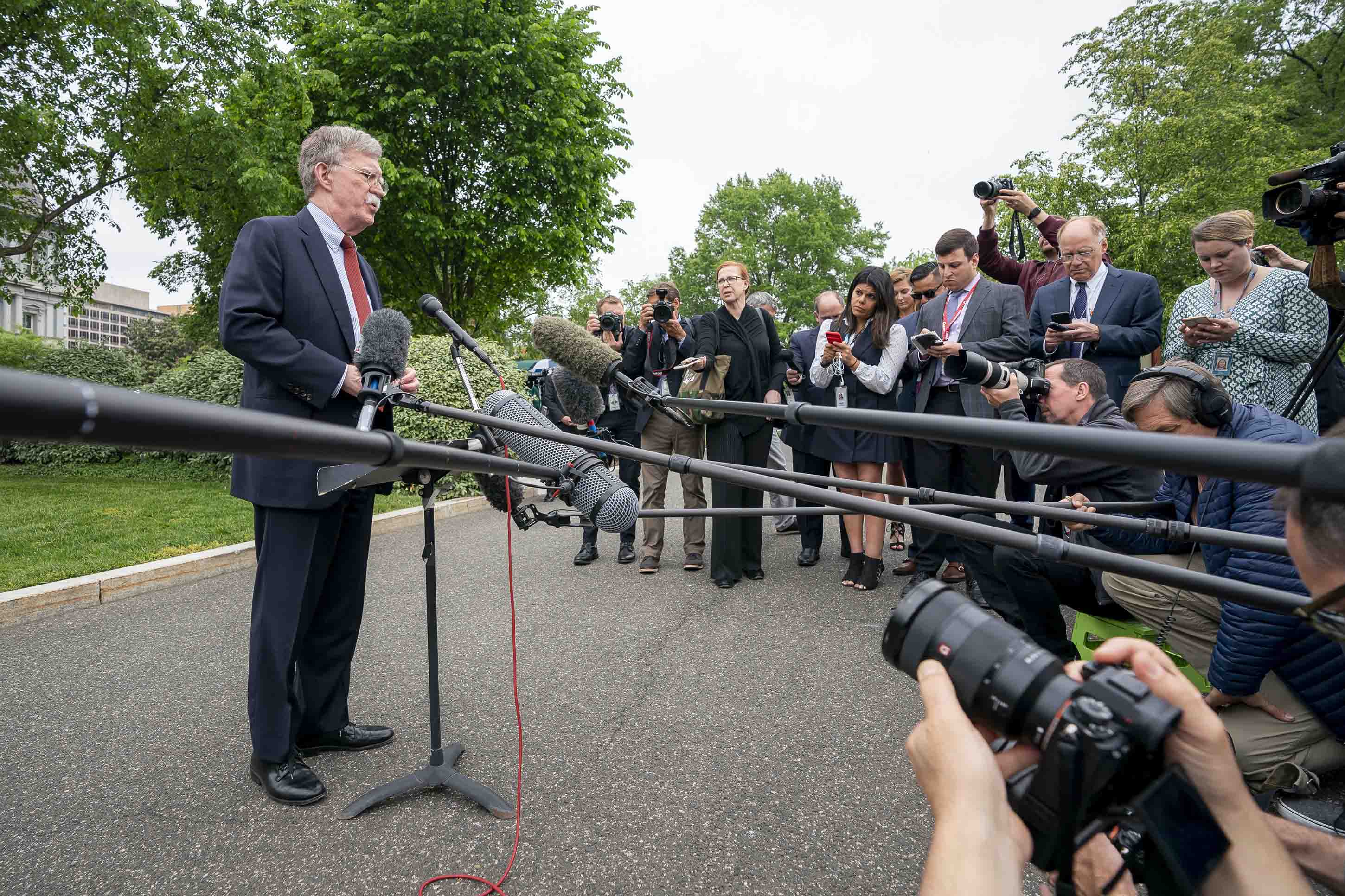 John Bolton stands in front of numerous microphones and reporters